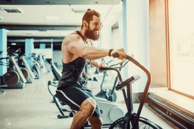 spor salonunda egzersiz bisikleti kullanan genç adam. Crossfit spor salonunda kardiyo egzersiz için hava bisiklet kullanarak fitness erkek.