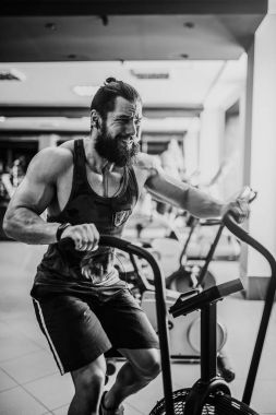 spor salonunda egzersiz bisikleti kullanan genç adam. Crossfit spor salonunda kardiyo egzersiz için hava bisiklet kullanarak fitness erkek.