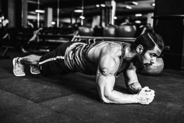 Çatı katı iç yerdeki egzersiz yaparken spor giyim ve iş tahta pozisyonu giyen kaslı genç adam