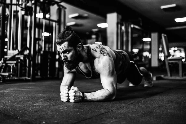 Muskulöser junger Mann in Sportbekleidung und in Plankenstellung beim Training auf dem Boden im Dachboden — Stockfoto