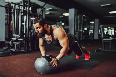 Gönderme yapan kaslı sakallı erkek spor salonunda top ups.