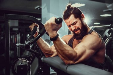 Pazı bir spor salonunda makinede için ağır egzersiz yapan erkek