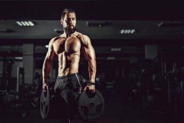 Spor salonunda dumbbells ile poz atlet kaslı vücut geliştirmeci adam.