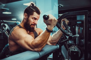 Pazı bir spor salonunda makinede için ağır egzersiz yapan erkek