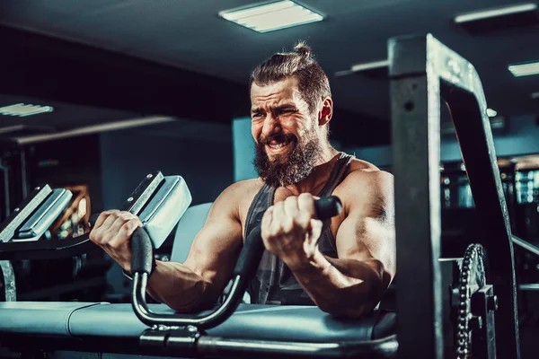 Pazı bir spor salonunda makinede için ağır egzersiz yapan erkek — Stok fotoğraf