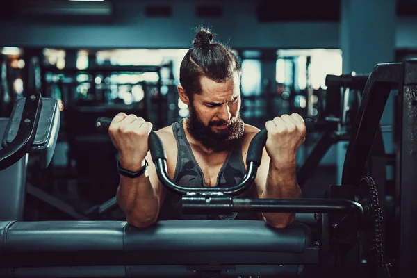 Pazı bir spor salonunda makinede için ağır egzersiz yapan erkek