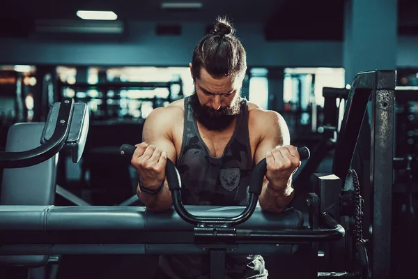 Pazı bir spor salonunda makinede için ağır egzersiz yapan erkek