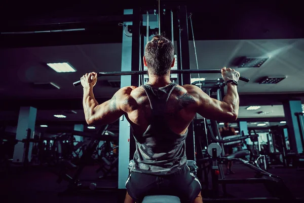 Starker Bodybuilder, der schwere Kraftübungen für den Rücken auf dem Gerät macht — Stockfoto