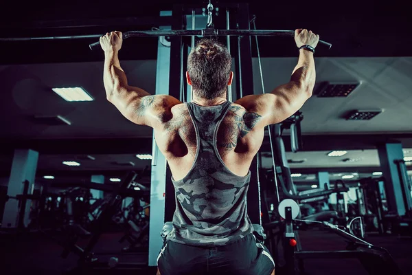 Arka üstünde makine için ağır egzersiz yaparak güçlü vücut geliştirmeci