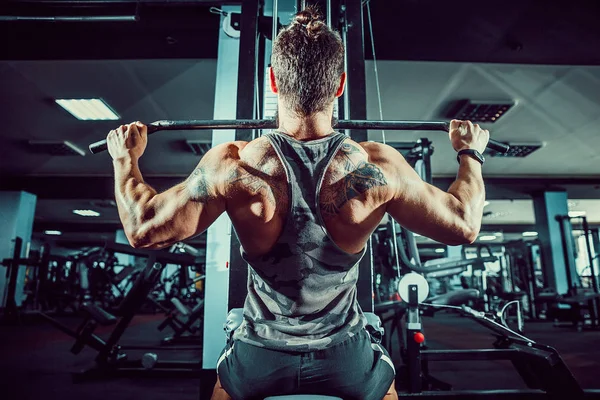 Arka üstünde makine için ağır egzersiz yaparak güçlü vücut geliştirmeci
