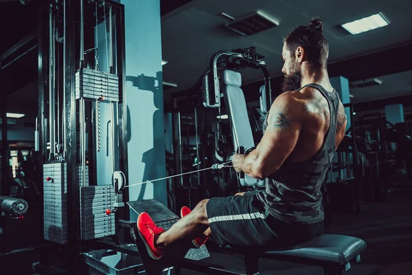 Culturista fuerte haciendo ejercicio de peso pesado para volver a la máquina — Foto de Stock