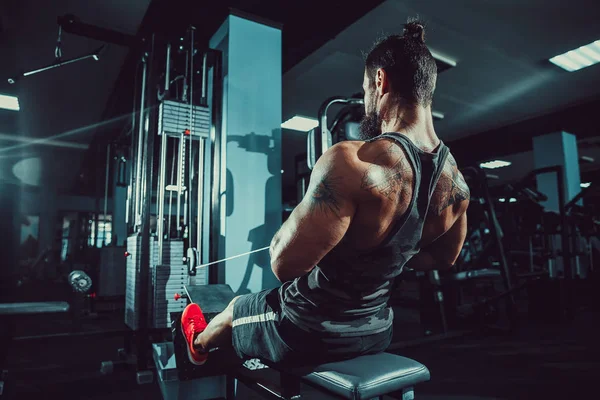 Arka üstünde makine için ağır egzersiz yaparak güçlü vücut geliştirmeci