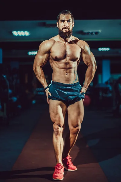Sportowiec kulturysta mięśni mężczyzna pozowanie w siłowni. — Zdjęcie stockowe