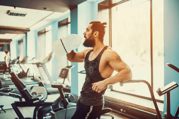 guy relaxing after workout and hold or drink water from big bottle in gym