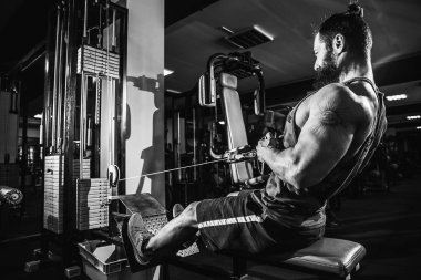 Arka üstünde makine için ağır egzersiz yaparak güçlü vücut geliştirmeci