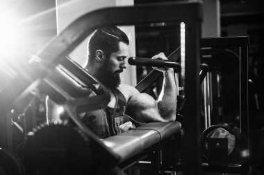 Pazı bir spor salonunda makinede için ağır egzersiz yapan erkek