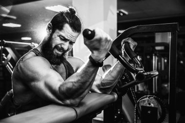 Pazı bir spor salonunda makinede için ağır egzersiz yapan erkek