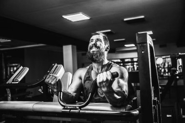 Pazı bir spor salonunda makinede için ağır egzersiz yapan erkek