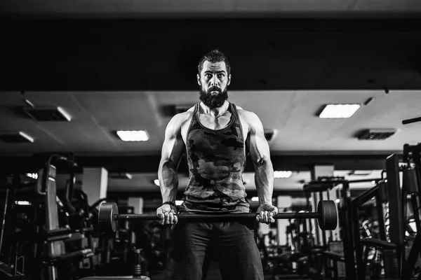 Muskulös bodybuilder killen gör övningar med hantel på gymmet — Stockfoto
