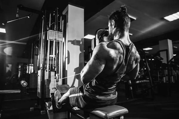 O halterofilista forte que faz o exercício pesado para trás na máquina — Fotografia de Stock