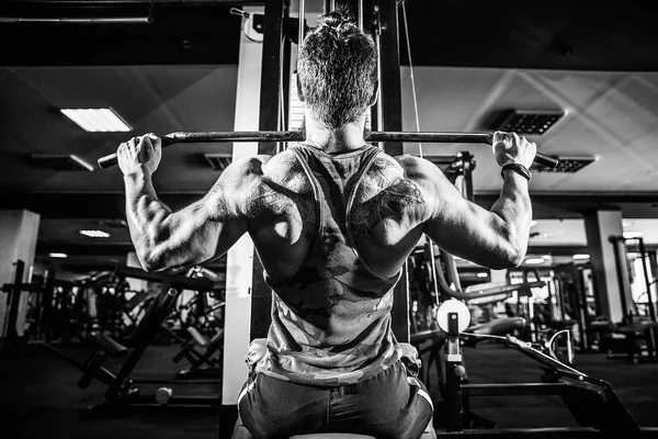 Arka üstünde makine için ağır egzersiz yaparak güçlü vücut geliştirmeci