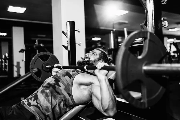 Jovem bonito fazendo exercício supino no ginásio — Fotografia de Stock