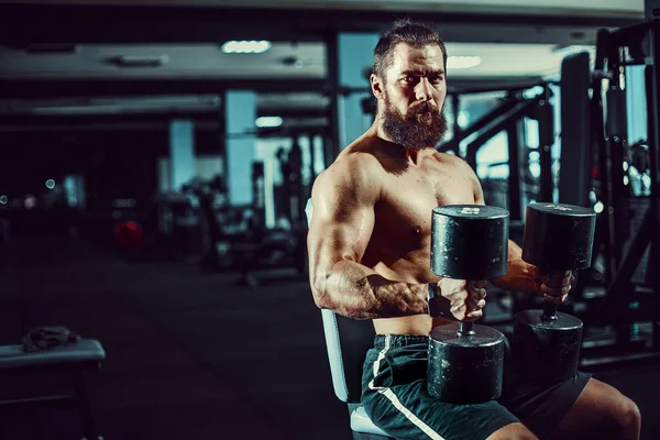 Сильний чоловік з великими м'язами, позує в камеру в спортзалі — стокове фото