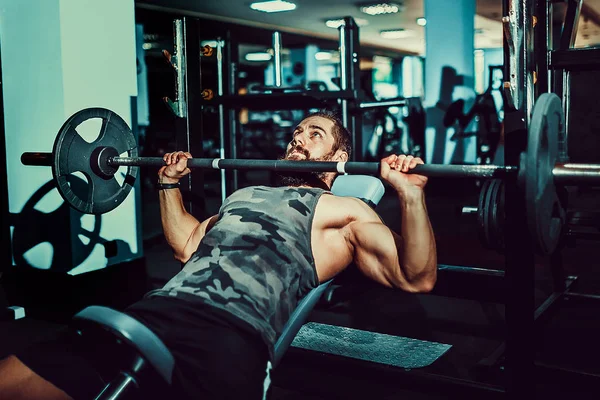 Jovem bonito fazendo exercício supino no ginásio — Fotografia de Stock