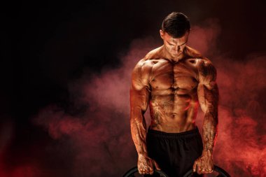 Onun kollarında dumbbells ile vücut geliştirmeci