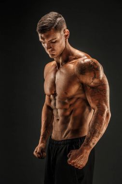 Vücut geliştirici pozu. Fitness, arka planda kaslı bir adam..