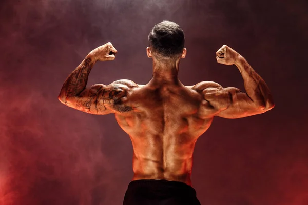 Bodybuilder presterende achterste dubbele biceps vormen — Stockfoto