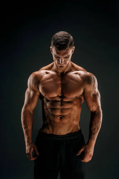 Vücut geliştirici pozu. Fitness, arka planda kaslı bir adam..