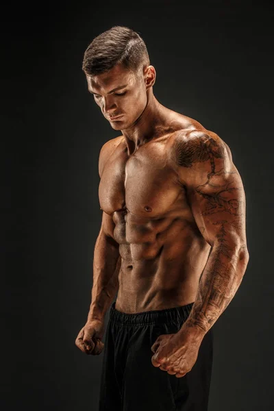 Vücut geliştirici pozu. Fitness, arka planda kaslı bir adam..
