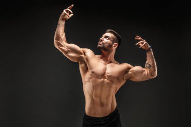 Vücut geliştirici pozu. Fitness, arka planda kaslı bir adam..
