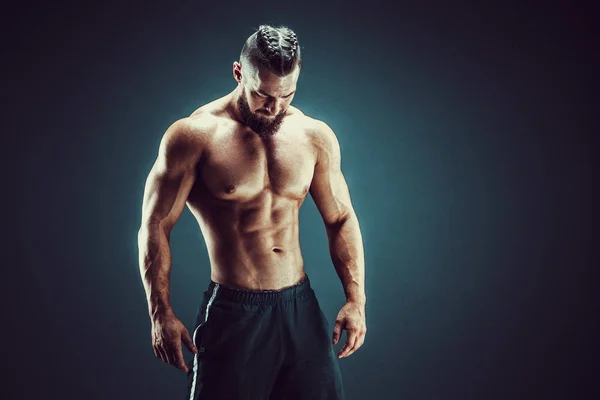 Vücut geliştirici pozu. Fitness, arka planda kaslı bir adam..