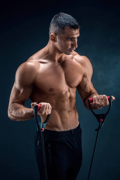 Fitness adamı esneme bandıyla egzersiz yapıyor. Lastik bantla egzersiz yapan kaslı bir sporcu. Lastik bantla çalışan adam. Form, spor, egzersiz, egzersiz ve sağlıklı yaşam tarzı. — Stok fotoğraf