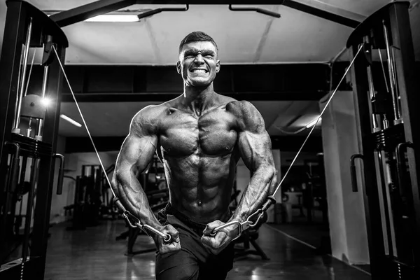 Bodybuilder werkt op zijn borst met cross-over kabel in gym. — Stockfoto