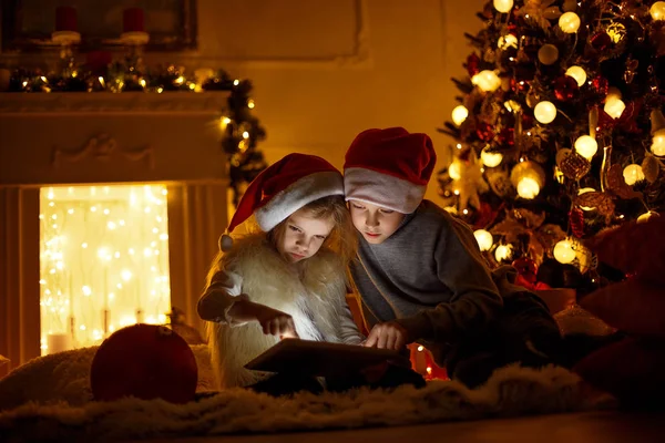 Opgewonden kinderen in de buurt van de kerstboom — Stockfoto