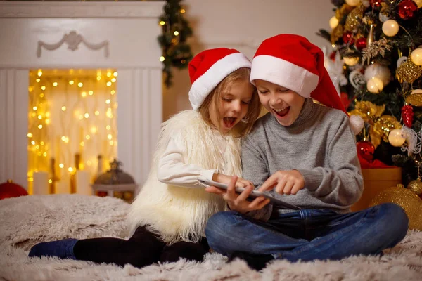 Κατάπληκτος παιδιών χρησιμοποιούν tablet κοντά στο χριστουγεννιάτικο δέντρο — Φωτογραφία Αρχείου