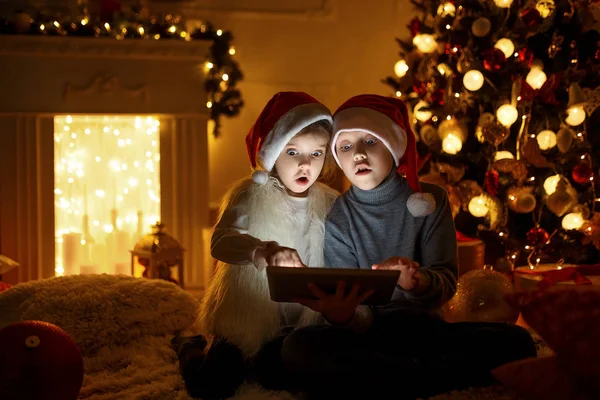 Hayret çocuklar Noel ağacı yakınındaki tablet kullanma — Stok fotoğraf
