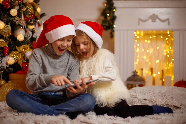 Zdumiony dzieci za pomocą tabletu w pobliżu choinki — Zdjęcie stockowe