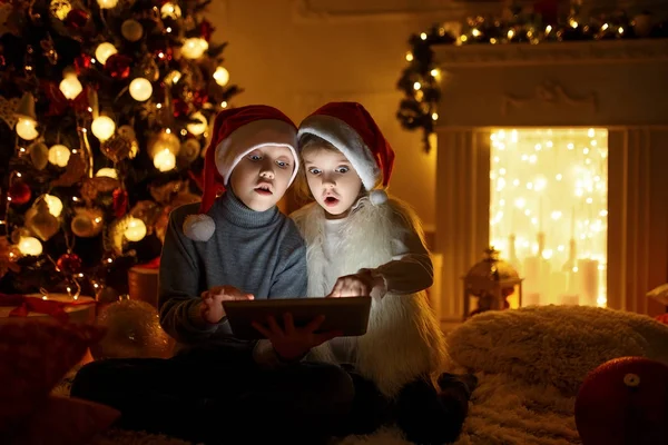 Κατάπληκτος παιδιών χρησιμοποιούν tablet κοντά στο χριστουγεννιάτικο δέντρο — Φωτογραφία Αρχείου