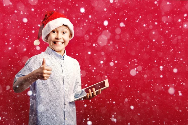 年轻的圣诞老人男孩做 ok 拇指竖起手势, 而持有的片剂 — 图库照片
