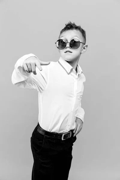 Niño con estilo en camisa blanca y pantalones negros con gafas de sol posando en el estudio — Foto de Stock