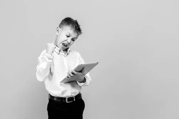 Niño feliz usando una tableta. Estudio de tiro aislado en amarillo . — Foto de Stock