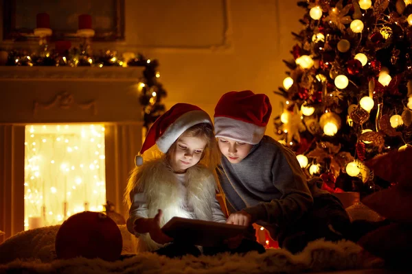 Opgewonden kinderen in de buurt van de kerstboom — Stockfoto