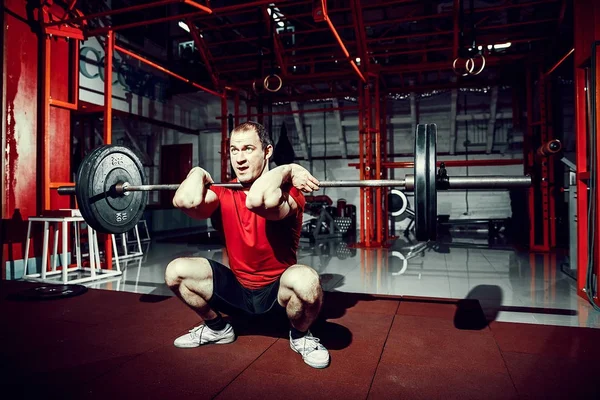 Muskelkräftiger Fitnessmann beim Kreuzheben einer Langhantel über dem Kopf in einem modernen Fitnesscenter. Functional Training. — Stockfoto