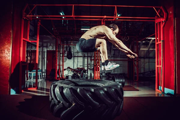 Trainingsmann springt auf Reifen in die Luft — Stockfoto