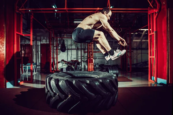 Trainingsmann springt auf Reifen in die Luft — Stockfoto
