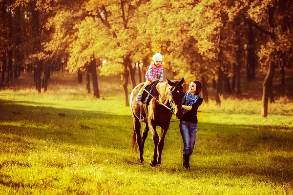 Malá holčička, jízda na koni se svou matkou, procházky v okolí — Stock fotografie